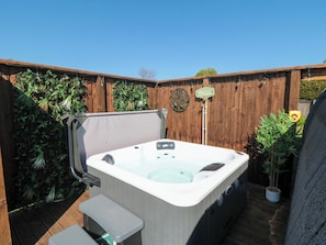 A hot tub with a bench, surrounded by a wooden fence and greenery. - Fern Folly (Whitby)