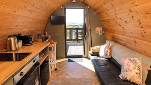 A cozy, wooden interior with a kitchenette, a sofa, and a view through a door. - Fern Folly (Whitby)
