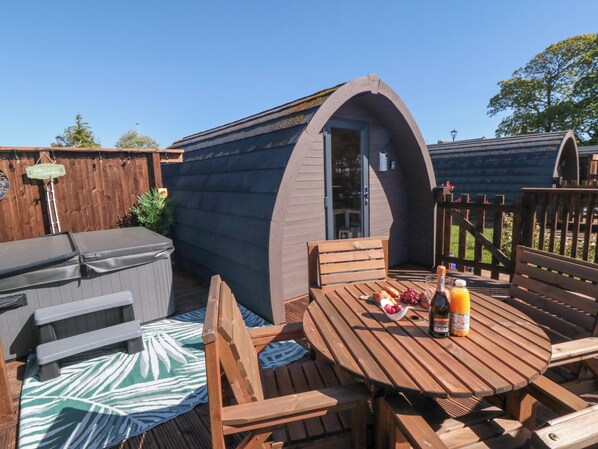 Een gezellig buiten zitgedeelte met een houten tafel, stoelen en een barbecue.