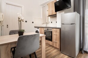 Una cocina moderna con armarios de madera, un refrigerador de acero inoxidable, un horno empotrado y un televisor de pantalla plana montado sobre el horno.