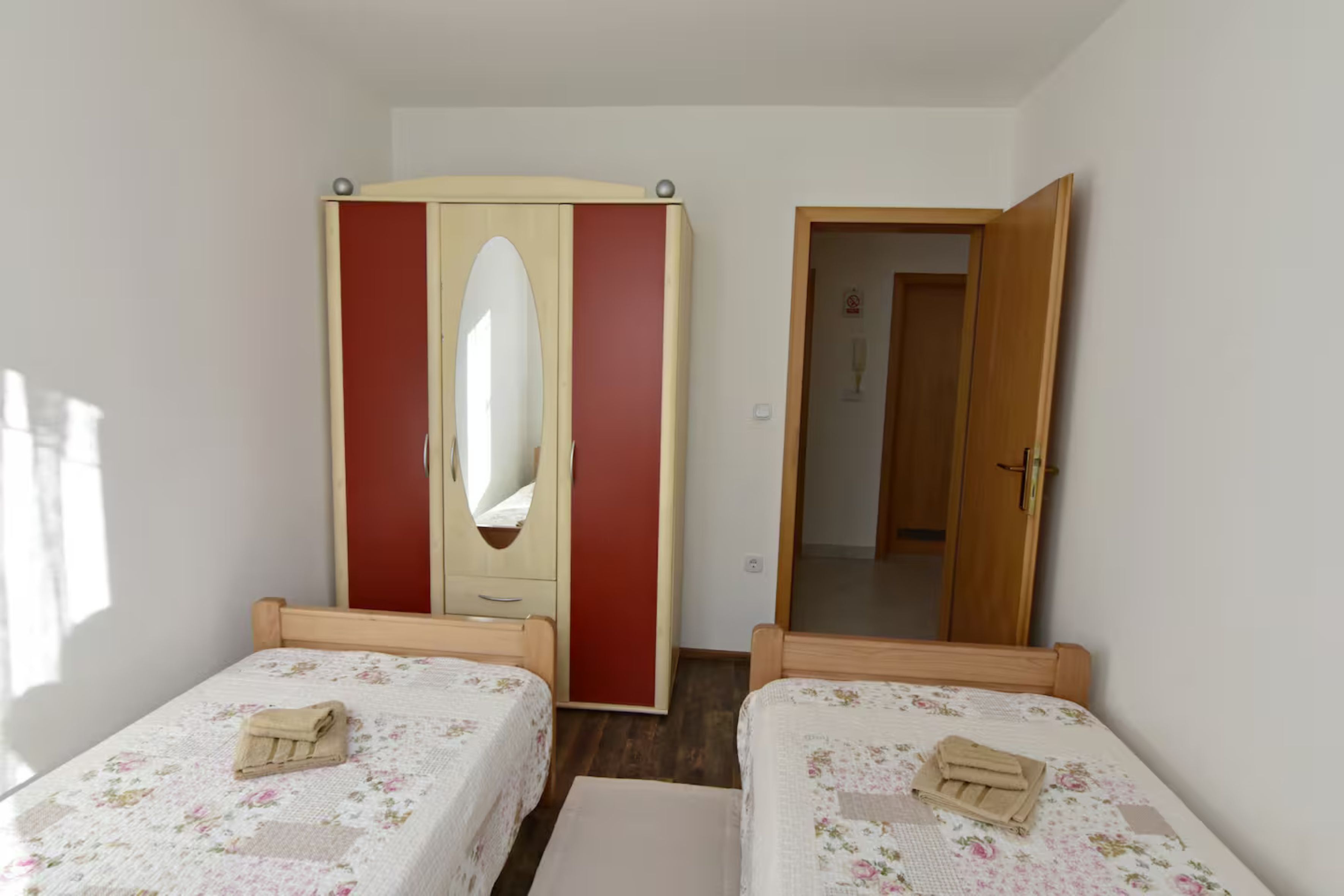 A bedroom with two single beds, a wardrobe, and a mirror.
