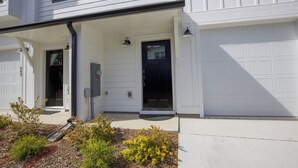 Ein zweistöckiges Haus mit überdachter Veranda, Garage und Eingangstür.