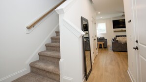Eine Treppe mit Teppichstufen und Holzbalkonen, die zu einem Raum mit Fernseher und einer Couch führt.