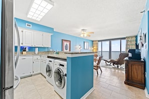 A kitchen with a washing machine, a ceiling fan, and a dining area with a view. - Oceanfront, well maintained, penthouse condo +Free Attraction Tickets! (North Myrtle Beach)