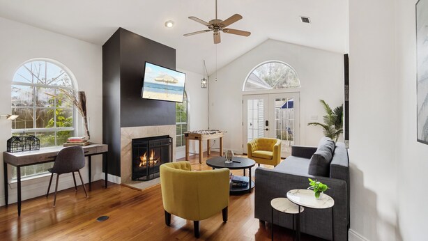 A modern living room with a fireplace, sofa, armchairs, and a television.
