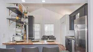A modern kitchen with a central island, bar stools, a built-in oven, and a stainless steel refrigerator.