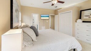 A bedroom with a bed, a ceiling fan, a TV, and a wardrobe.