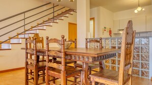 Ein Essbereich mit Holztisch und Stühlen, eine Treppe und eine Küchenzeile mit Schränken.