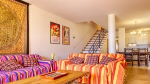 Ein Wohnzimmer mit einer Sofagarnitur, einem Holztisch und einer Treppe, die zu einem Essbereich führt.