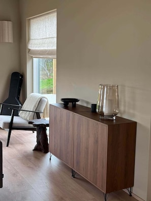 A modern room with a wooden cabinet, a chair, and a guitar.