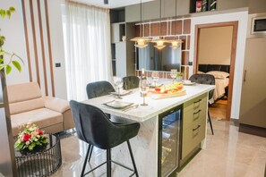 A modern kitchen with a central island, bar stools, a dining table, and a built-in refrigerator. - Modern apartment Zeravica with balcony  (Drniš)
