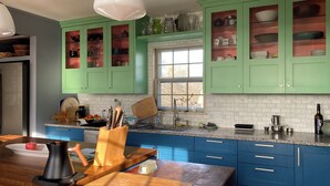 Una cucina con mobili verdi, un piano di lavoro in marmo e una finestra.