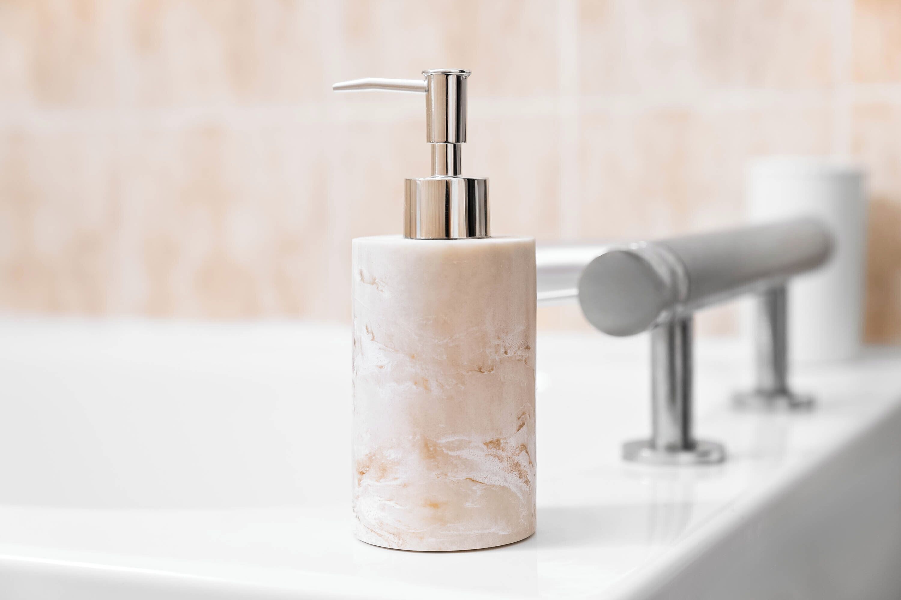 A bathroom with a marble soap dispenser on a white sink.
