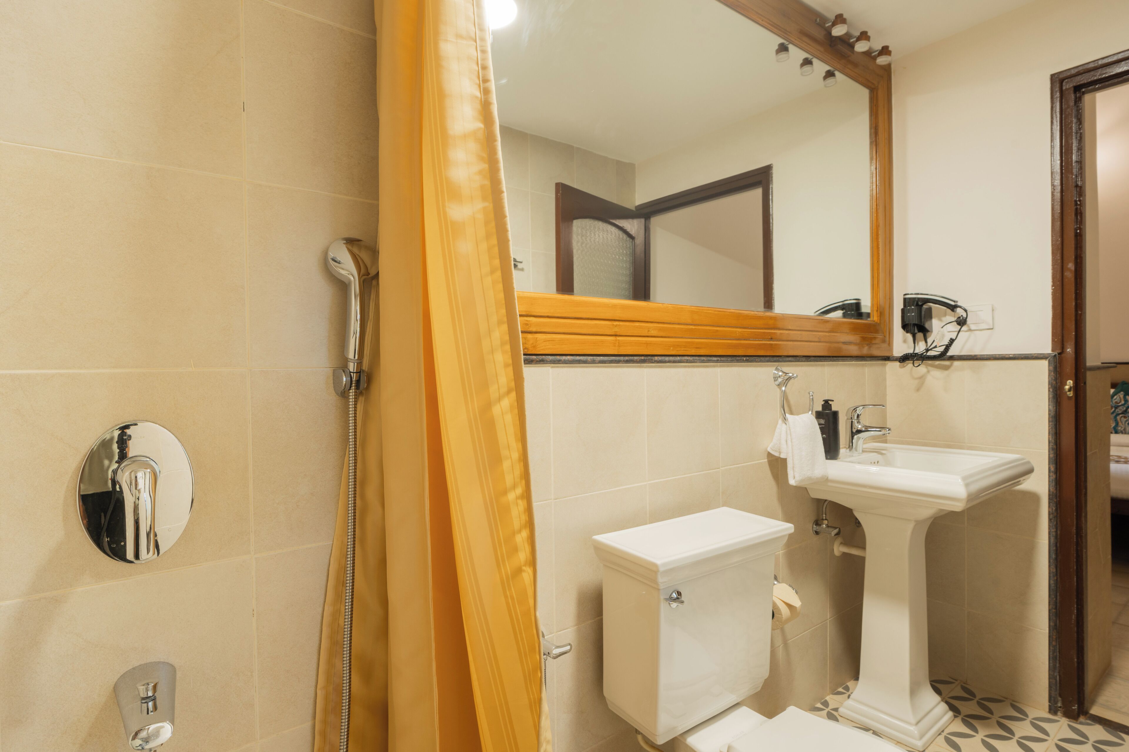 A bathroom with a shower, toilet, sink, and mirror.