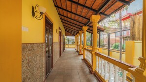 A corridor with a tiled floor, yellow walls, and a wooden ceiling. - Alaya Stays Casa do Mar Heritage 4BHK (Calangute)