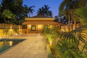 A resort with a swimming pool, a covered patio, and tropical vegetation.
