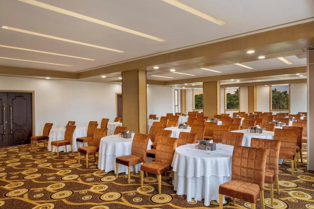 A conference room with round tables and chairs, a patterned carpet, and a modern ceiling design.