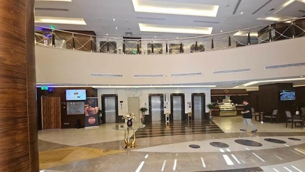 Un hall d’entrée spacieux avec un plafond haut, un comptoir de réception central et un balcon situé au deuxième étage.