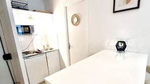 A compact kitchen with a microwave, sink, and cabinets, a white door with a circular handle, and a framed abstract art piece on the wall. - Studio Montorgueil Paris 2 (Paris)