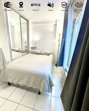 Een moderne hotelkamer met een bed, een bureau, een lamp en een raam met gordijnen.