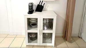 A white cabinet with glass doors containing dishes and a coffee maker. - Studio Montorgueil Paris 2 (Paris)