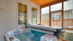Ein Whirlpool mit einer Holzterrasse, großen Fenstern und Blick auf einen Holzzaun.