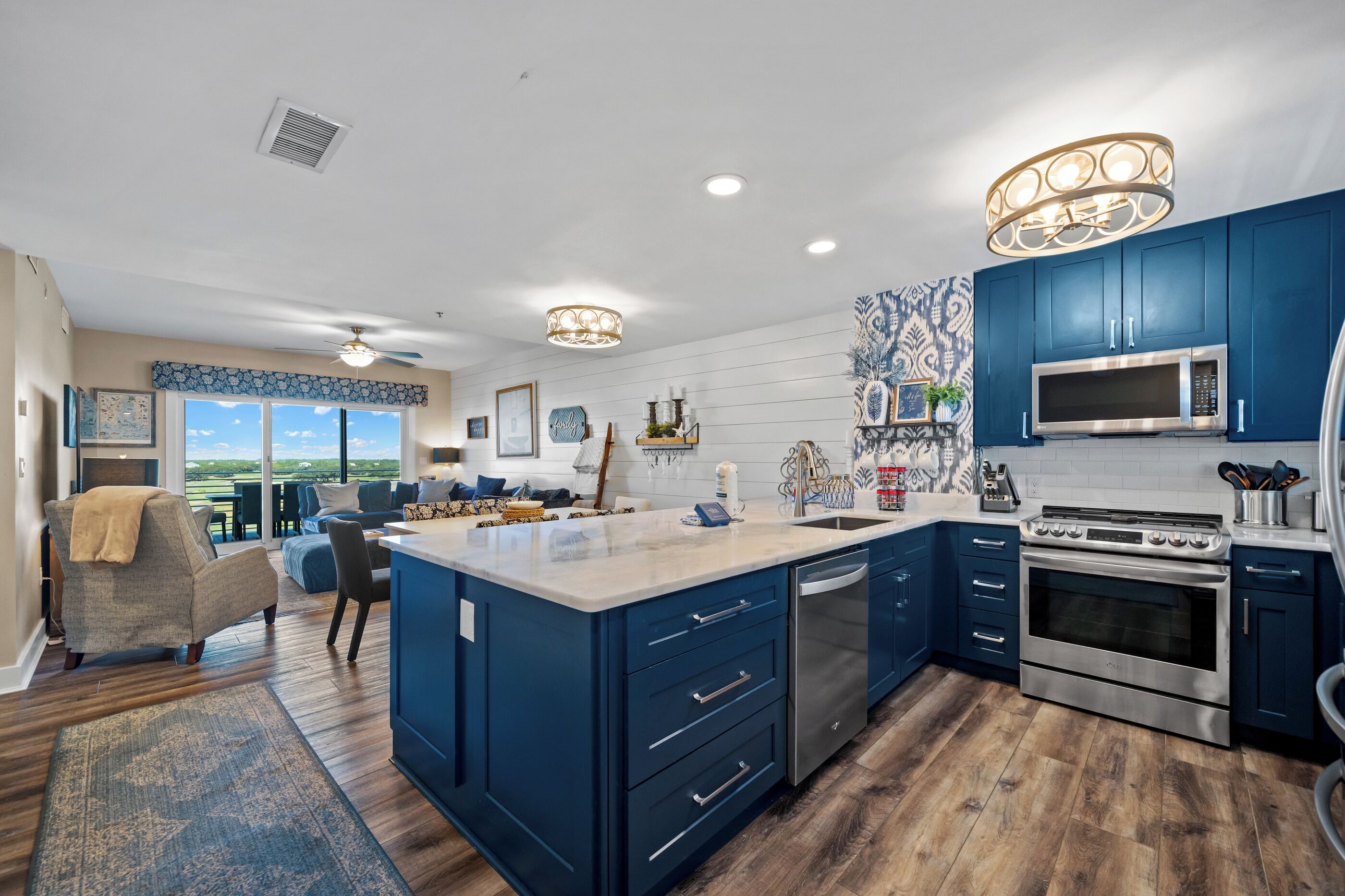 A modern kitchen with blue cabinets, stainless steel appliances, and a large island.