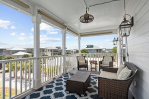 A covered porch with wicker furniture, a table, and a hanging light fixture. - Formerly Beach Daze at Kiva Dunes (Gulf Shores)
