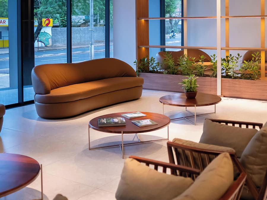 Un intérieur moderne avec un canapé, deux tables basses et un coin salon offrant une vue sur la rue.