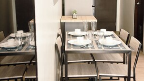 A dining area with a table set for four, chairs, a refrigerator, and a small plant on the wall. - City-View + Spacious Unit | Across Trinoma Mall (Quezon City)