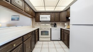 A kitchen with dark wood cabinets, a white microwave, an oven, and a dishwasher. - Pelican Inlet C222: steps to pool, tennis; boat ramp and storage available (Saint Augustine)