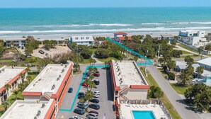 An aerial view of a coastal hotel with a parking lot, swimming pool, and ocean view. - Pelican Inlet C222: steps to pool, tennis; boat ramp and storage available (Saint Augustine)