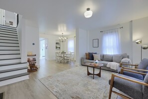 Ein modernes Wohnzimmer mit Treppe, Essbereich und Sofa.
