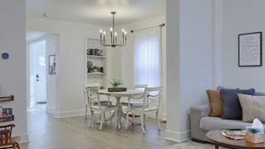 A modern living room with a grey sofa, a coffee table, and a dining area with a white table and chairs. - Hot Tub Retreat Between Philly & Lancaster (Parkesburg)