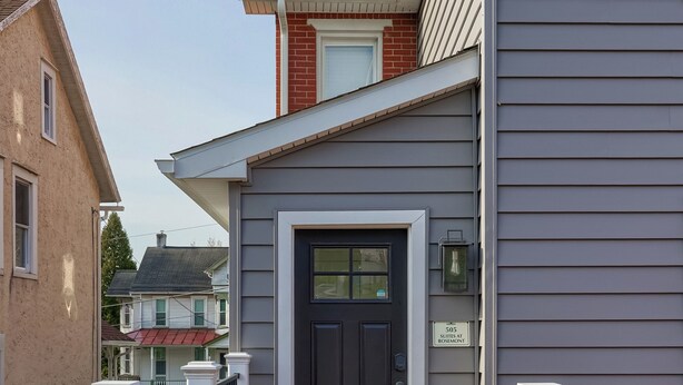 A residential building with a dark front door, a small porch, and a wooden deck. - Hot Tub Retreat Between Philly & Lancaster (Parkesburg)