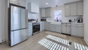 A modern kitchen with white cabinetry, stainless steel appliances, and a window providing natural light. - Hot Tub Retreat Between Philly & Lancaster (Parkesburg)