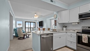 A modern kitchen with white cabinets, a dishwasher, a microwave, and an oven. - Dune Daze-Ocean Front Condo in Dunescape Villas (Atlantic Beach)