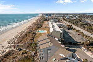 Ein Hotel an der Küste mit Blick auf den Strand, einem Schwimmbad und einem Parkplatz.