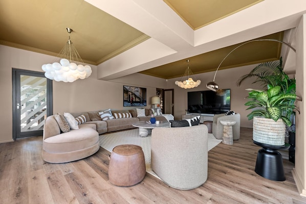 A modern living room with a sectional sofa, round coffee table, and a large flat-screen TV. - Luxury Camps Bay 5 Star w Gym Pool Kinvara Villa (Cape Town)