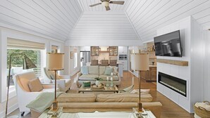 Ein modernes Wohnzimmer mit Deckenventilator, Kamin und Wandfernseher.