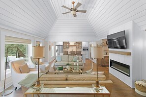 Ein modernes Wohnzimmer mit Deckenventilator, Kamin und Wandfernseher.