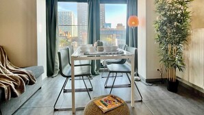 A modern living room with a dining area, large windows, and a view of a cityscape. - Suite in Antwerp Near Meir Shops (Antwerp)