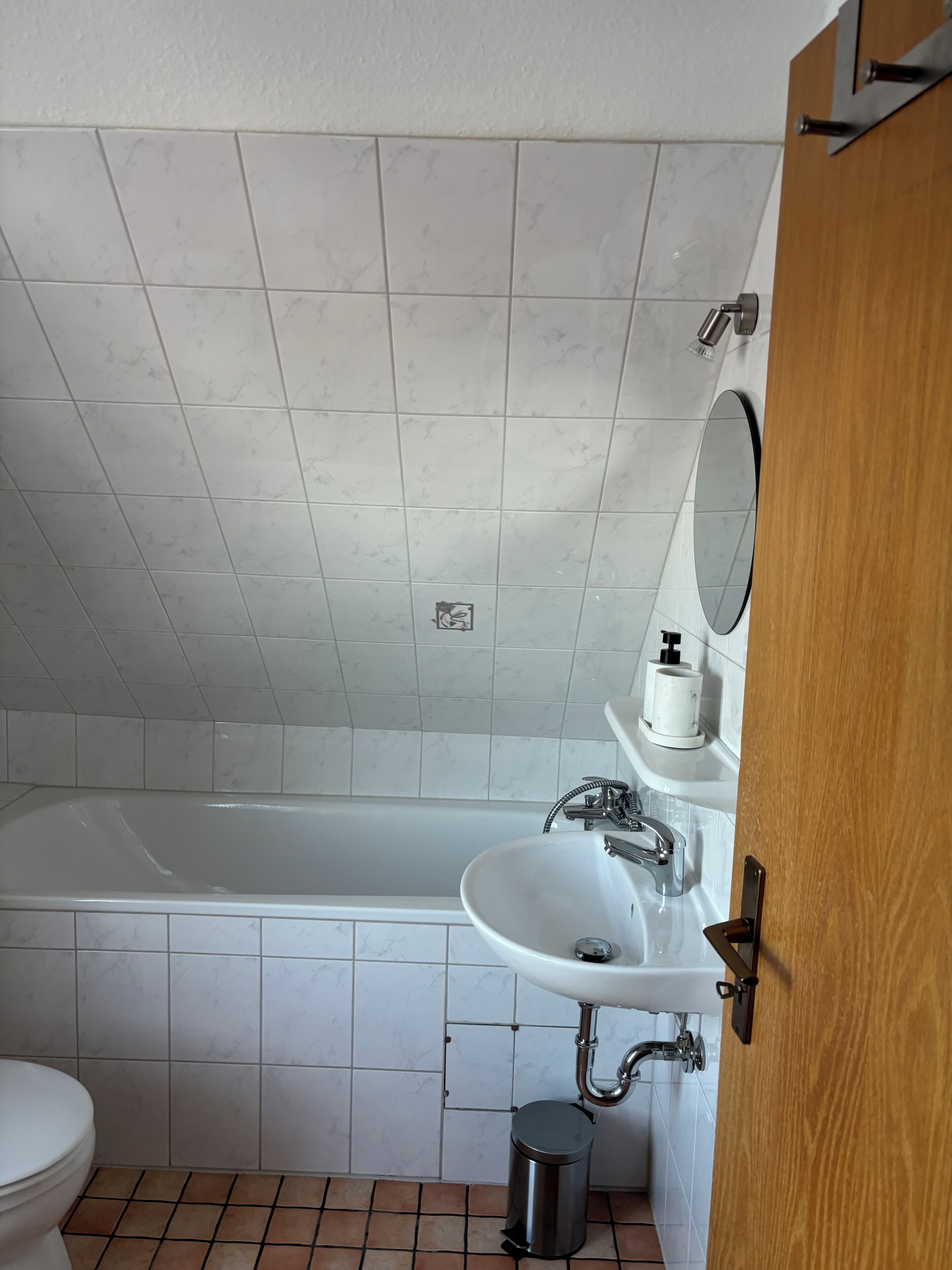 Une salle de bain équipée d’une baignoire, d’un lavabo, de toilettes et d’une poubelle.