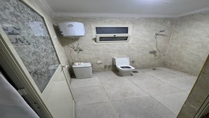 Une petite salle de bain comprenant des toilettes, une douche et un radiateur fixé au mur.