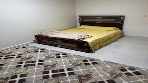 Une chambre à coucher avec un lit, un tapis à motifs et un mur uni.
