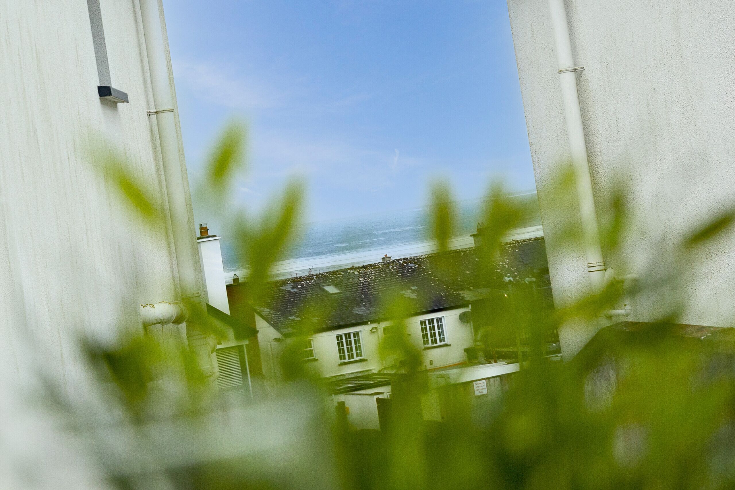 A coastal building with a view of the sea, large white structures, and greenery in the foreground.