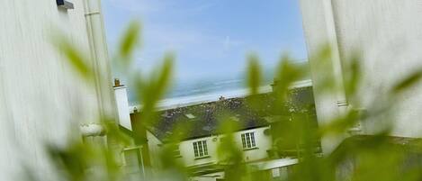 A coastal building with a view of the sea, large white structures, and greenery in the foreground.