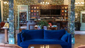 A cozy lounge area with a blue sofa, a bookshelf, and a bar area with wine bottles. - East Austin Bungalow w BBQ Firepit Fun Yard (Austin)