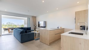 A modern kitchen with a built-in island, a dining area with a sofa, and a large window offering a view. - Aquamarine at Blue Bay Beach Golf Resort (Sint Michiel)