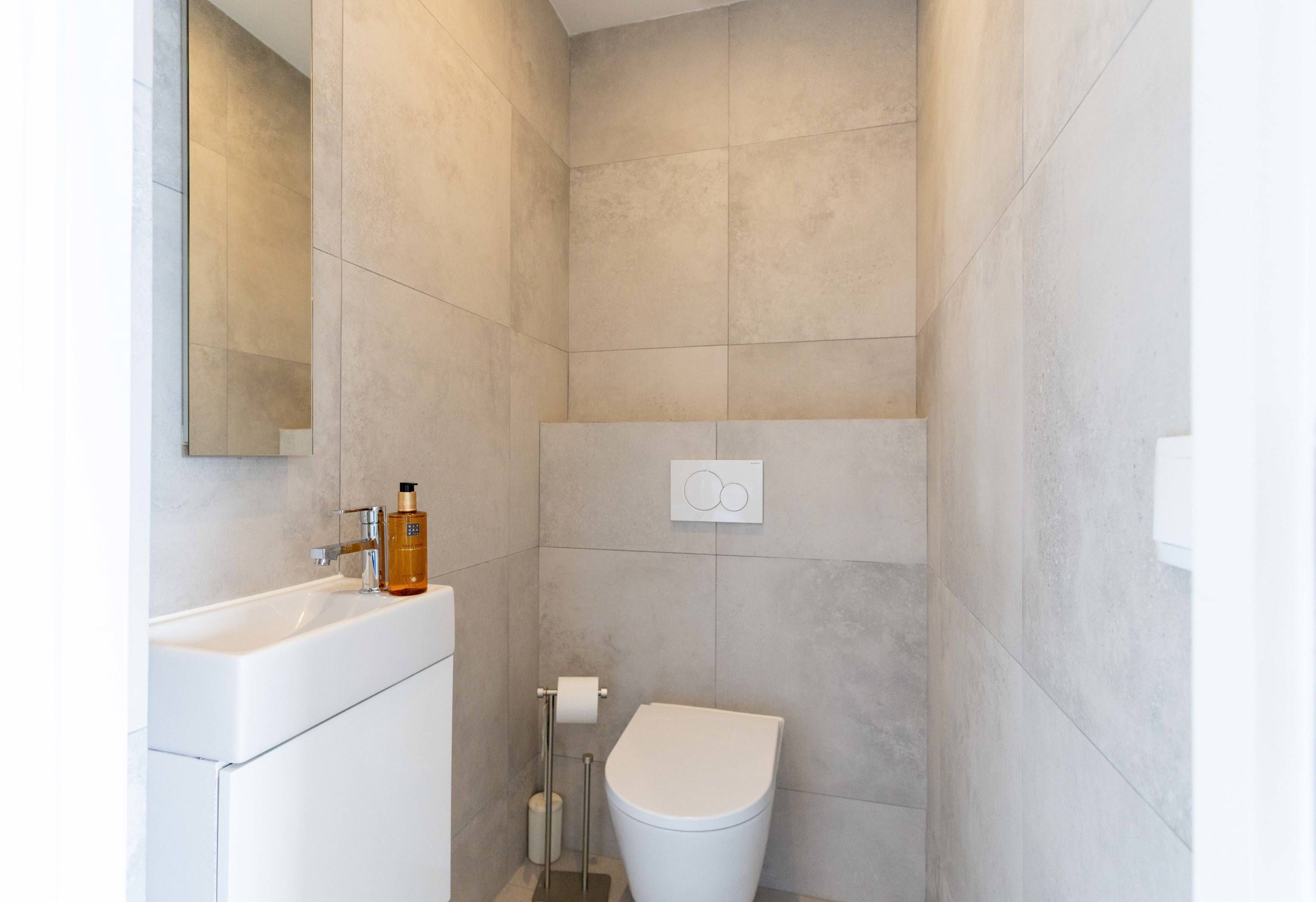 A modern bathroom with a white sink, toilet, and shower area.